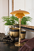 Tischlampe, schwarz-goldene Schalen und Zimmerpflanze in dekorativem Übertopf