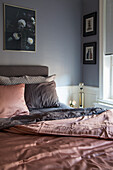 Double bed with satin bed linen in the bedroom with grey wall