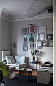 Corner lounge chair, above it photo gallery on grey wall and stucco work in living room