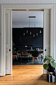 View through open sliding doors into the dining room with black furniture and black wall