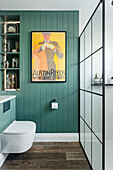 Bathroom with green-painted wood paneled wall and industrial-style shower enclosure