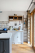 Kitchen with light grey cabinet fronts, antique cupboard, and wall tiles