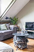 Graues Polstersofa, TV-Möbel und Couchtisch mit Korb für Kissen im Dachzimmer