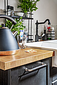 Kettle on kitchen base cabinet with wooden counter top