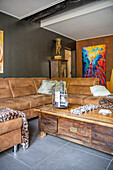 Light brown sectional sofa and vintage wooden table in a living room with dark wall