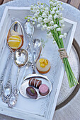 Chocolates with silverware and lily of the valley on a wooden tray