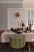 Festlich gedeckter Weihnachtstisch mit Kerzen, Polsterstühle mit Samtbezug um den Tisch
