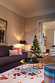 Purple upholstered sofa and small Christmas tree in illuminated living room