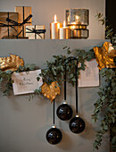 Weihnachtsgirlande an der Wand, darüber in Goldpapier verpackte Geschenke und Kerzen