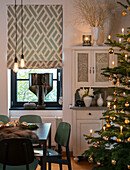 Dining area with green table, sideboard, and illuminated Christmas tree