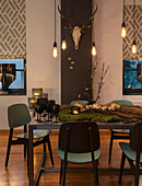 Dining table decorated with moss and Christmas ornaments, pendant light above it