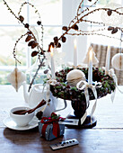 Adventskranz mit weißen Kerzen und Lärchenzweige in Ballonflasche auf Holztisch