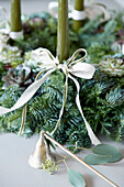 Advent wreath made of coniferous branches with green candles and little bells