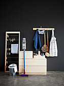 Utensils for spring cleaning, sideboard and clothes horse in room with black wall