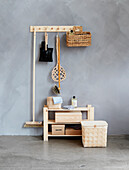 Wooden shelf with tidy boxes, above it a coat rack with cleaning utensils