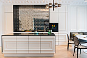 White kitchen island black top and antique looking mirror tiles in open-plan kitchen
