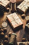 Christmas gifts, spool of yarn, walnuts and cones on wooden table