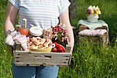 Frau trägt Picknickkorb mit Gebäck und Erdbeeren