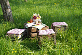 Picknickplatz aus Holzkisten mit Decke und Kissen im Garten