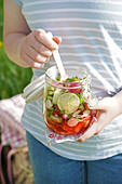 Preserving jar with fresh vegetable snack and wooden fork outdoors