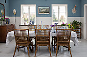 Set table with rattan chairs and dresser in dining room with blue walls and white tiles