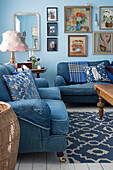 Blue sofas with denim upholstery and picture gallery in the living room with light blue walls
