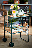 Flowers, tea set, cakes and garden tools on serving trolley
