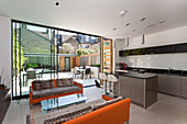 Orangefarbene Polstersofas mit Auflage und moderne Einbauküche in offenem Wohnraum