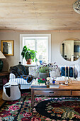 Cozy sofa with cushions, wooden coffee table and kilim rug in rural living room