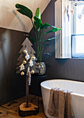 Badezimmer mit Deko-Tannenbaum, freistehender Badewanne und Zimmerpflanze