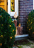 Decorative wooden sculptures in candle look at the Christmas-lit entrance to the house