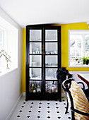 Crockery cabinet in front of yellow wall in dining room