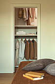 A view across a bed into a walk-in wardrobe