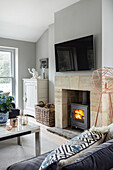 Wood stove with burning fire, TV above in the living room