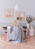Round table with floor-length tablecloth and chairs in the room in pastel and earth tones