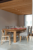 Solid wood dining table with upholstered chairs on concrete floor