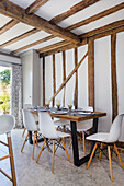 Essbereich mit Klassikerstühlen in offener Küche mit Holzbalkendecke