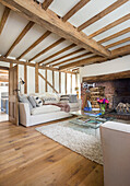Light sofa and rustic fireplace in the living room with wood-beamed ceiling