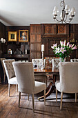 Antique table and chairs with light upholstery in dining room with oak panelling