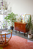 60s sideboard with pictures, house plants, and rattan coffee table with glass top in living room