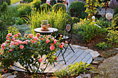 A romantic seating area on wooden deck with 'Cippendale' roses in the foreground