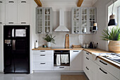 White kitchen with wooden worktop and black side-by-side refrigerator