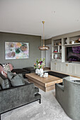 Grey sofa set, coffee table, large-format painting on the wall and shelving unit in the living room