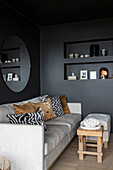 Light sofa with cushions in the living room with black walls
