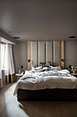 Doppelbett mit raumhohem Betthaupt im Schlafzimmer