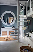 Sink with large mirror above on grey wall in bathroom, spiral staircase leads to sleeping area