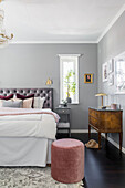 Double bed with grey headboard in the bedroom in grey tones