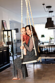 Mother with baby swinging at home