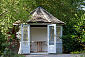 Teehaus mit geöffneten Flügeltüren im Garten