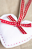 White felt heart with red decorative ribbon